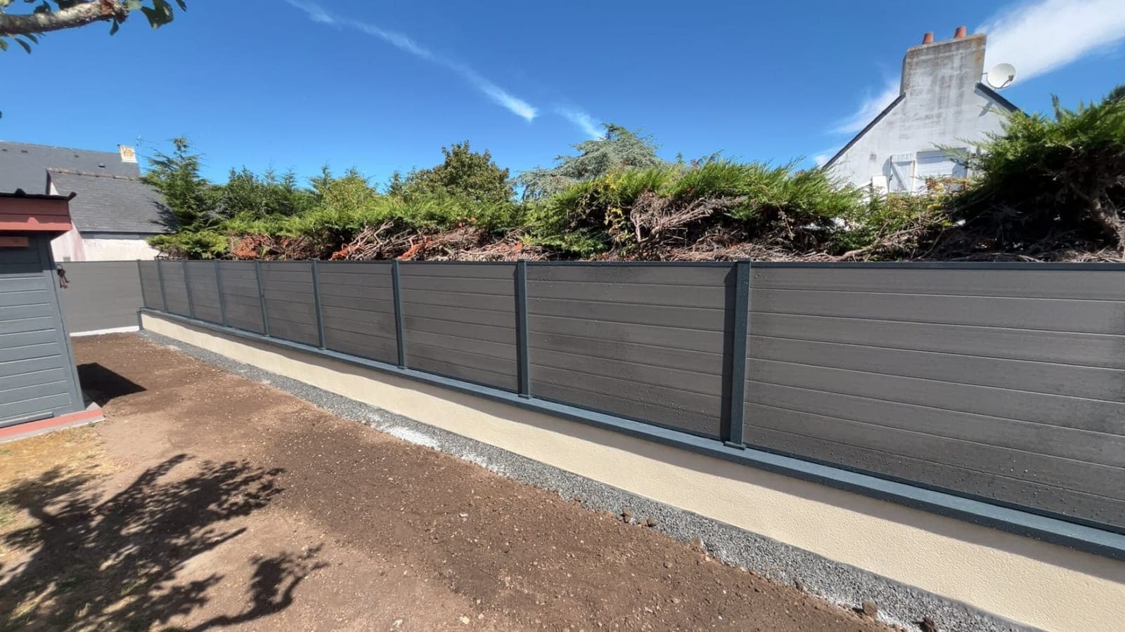 Muret enduit surmonté de panneaux composites gris sur poteaux aluminium